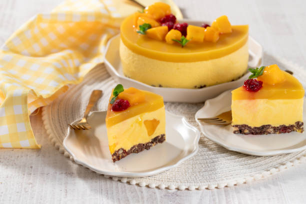 istock Delicious no bake mango cheesecake with fresh diced mango pulp and raspberry topping on white wooden table. 2168788831