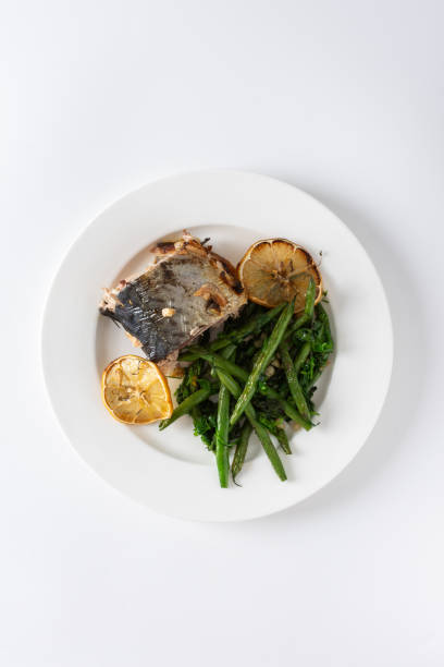 istock This savory dish features baked green beans with onions and tender mackerel, served on a plate against a white background, offering a healthy and balanced gourmet meal 2168789825