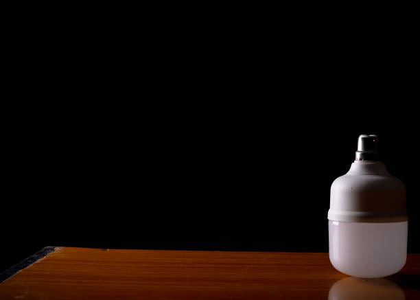 istock Energy-efficient LED Bulb on Wooden Surface with Dark Background 2168789958