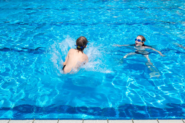 Two children enjoying a sunny day at an outdoor swimming pool