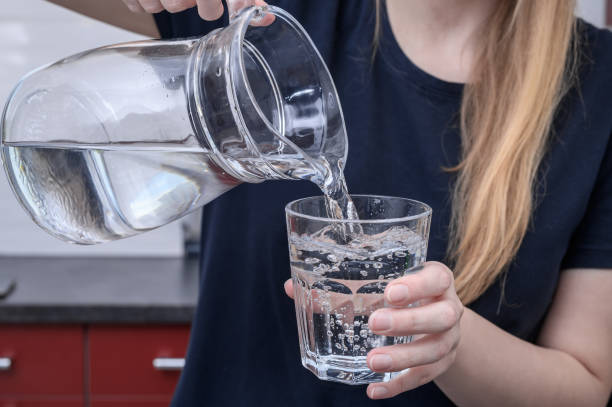 istock Mineral water poured into a glass held in the hand 2168794860