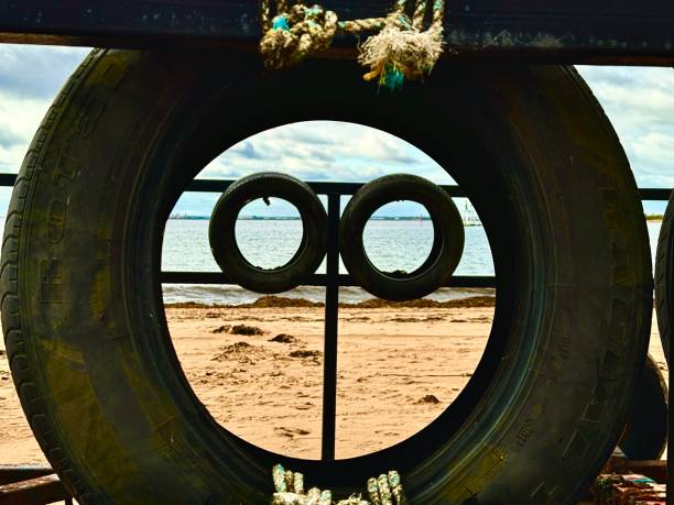 istock Looking through a car tyre at two more car tyres on a beach 2168797113