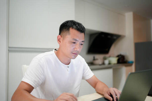 istock The man works on the computer at the kitchen table at home 2168806312