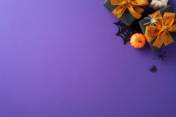 istock Halloween gift boxes with orange bows, mini pumpkins, and spider decorations on a purple background. Festive and spooky holiday decor 2168812070