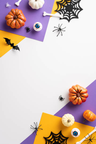 istock Vibrant Halloween vertical flat lay featuring pumpkins, spider webs, bats, and spooky eyeball decorations in a colorful arrangement 2168812076