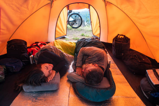 Couple inside a camping tent with a bicycle next to it and outside