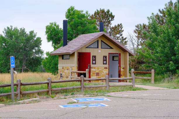 Outdoor restroom facility with handicapped parking spaces surrounded by trees and greenery along a hiking trail in a nature park.
