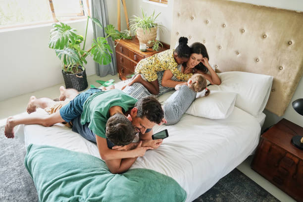 Parents with children (18-22 months, 6-7, 8-9) relaxing on bed