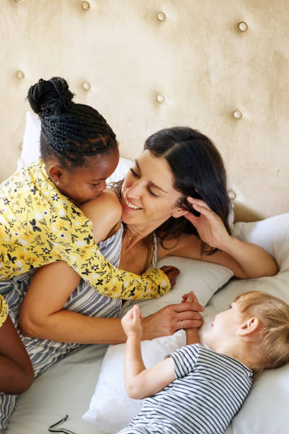 Mother with daughters (18-22 months, 6-7) on bed