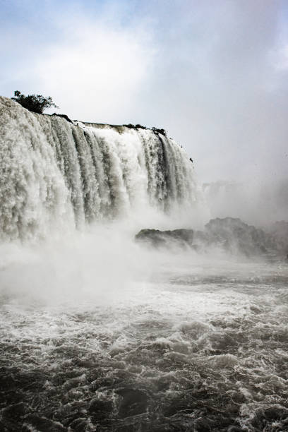 Close-up of a massive waterfall, with roaring water cascading into a misty, turbulent pool below