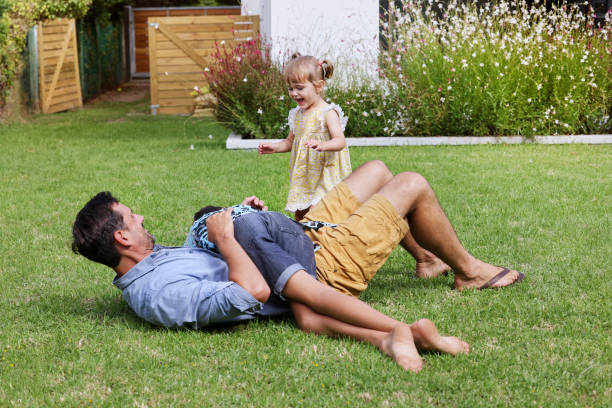 Father with children (18-22 months, 8-9) playing on back yard