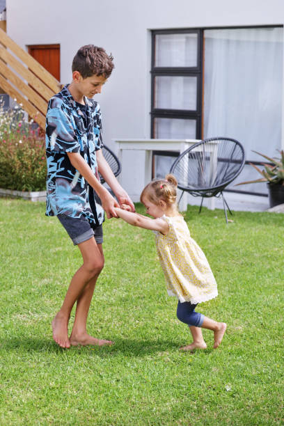 Brother (8-9) and sister (18-22 months) playing on back yard