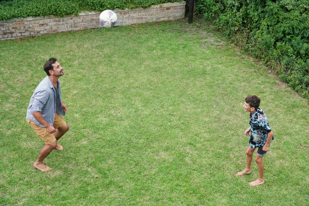 istock Father and son (8-9) playing with ball on back yard 2168837194