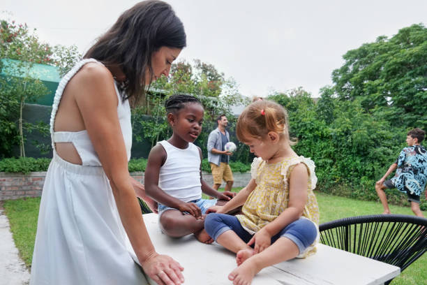 Parents with children (18-22 months, 6-7, 8-9) playing on back yard