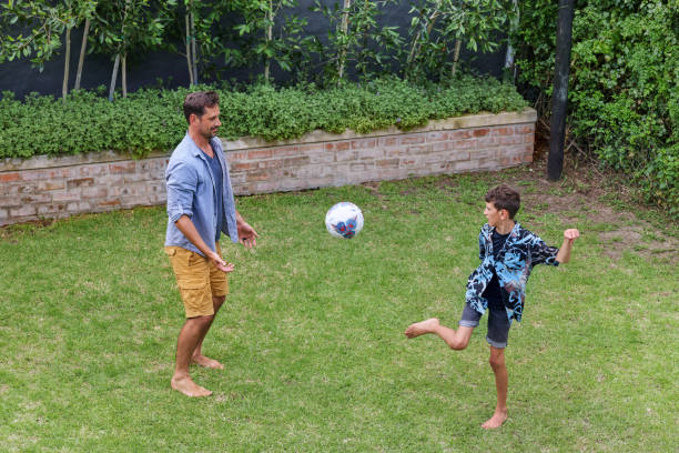 istock Father and son (8-9) playing with ball on back yard 2168838033