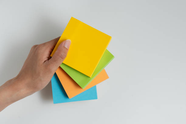 Woman hand holding stack of multicolored adhesive notes against isolated white background