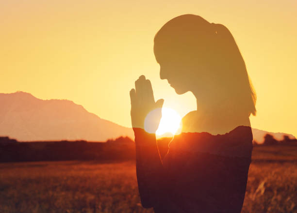 Woman praying at sunset.