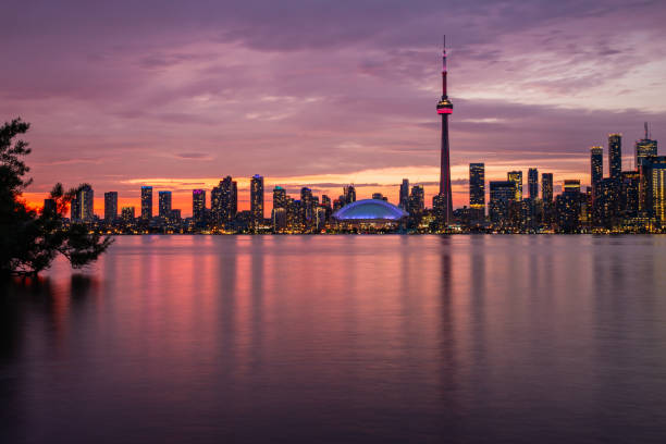 An airplane is flying over Lake Ontario. Toronto skyline can be seen in the background.