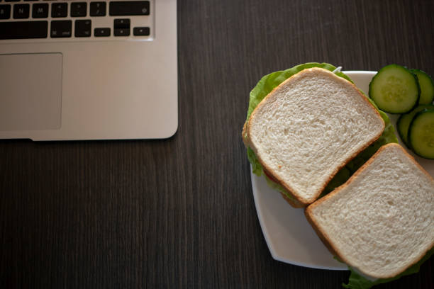 Coffee cup and sandwich on table with laptop