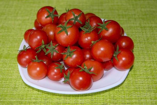 Beautiful ripe red cherry tomatoes on a white saucer close-up.