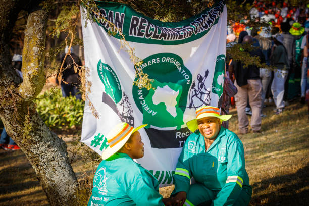 Two african recyclers pose in front of the flag. A parade and various art performances were held to promote and celebrate recycling towards saving the environment for future generations.
