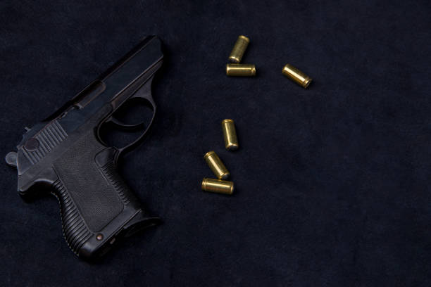 istock 9mm pistol and bullets on a black leather background, top view 2168858124