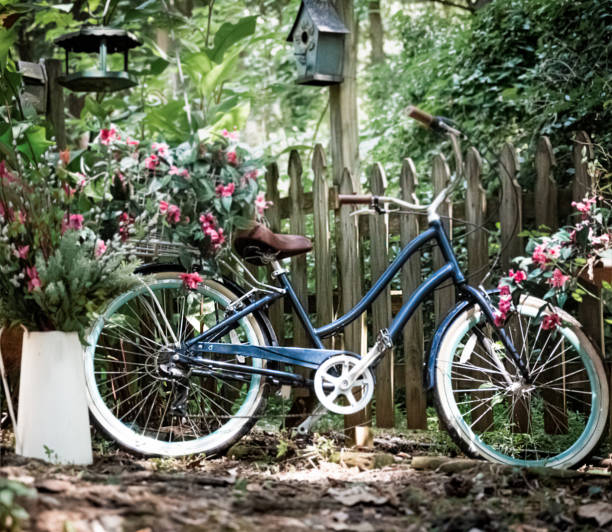 A blue bicycle with flowers and a picket fence