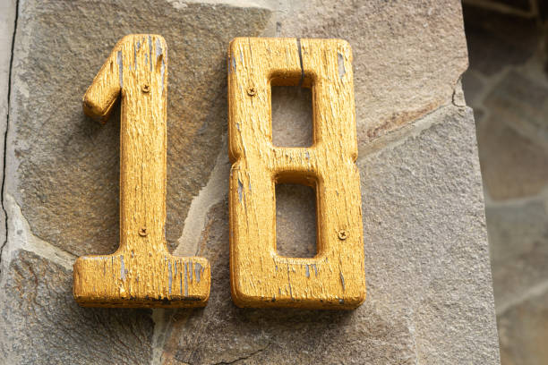 istock Yellow number eighteen on a stone wall 2168864572
