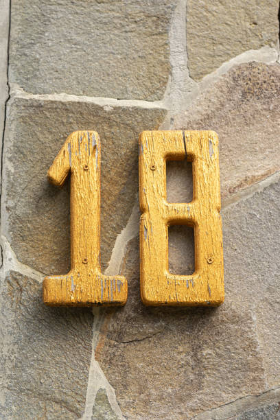 istock Yellow number eighteen on a stone wall 2168864880