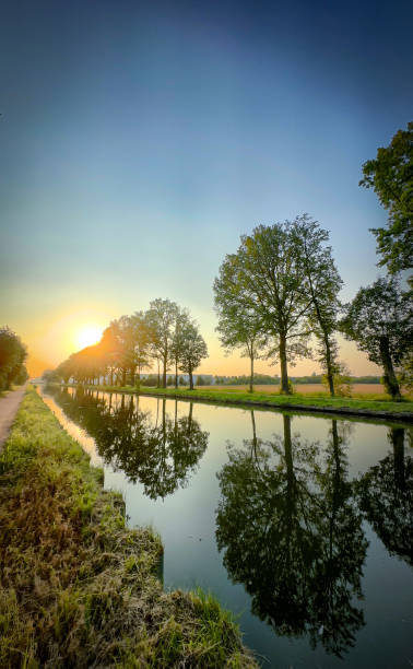 istock Experience a Serene Sunset by the Beautiful and Reflective Riverbank Surrounded by Lush Trees 2168901805