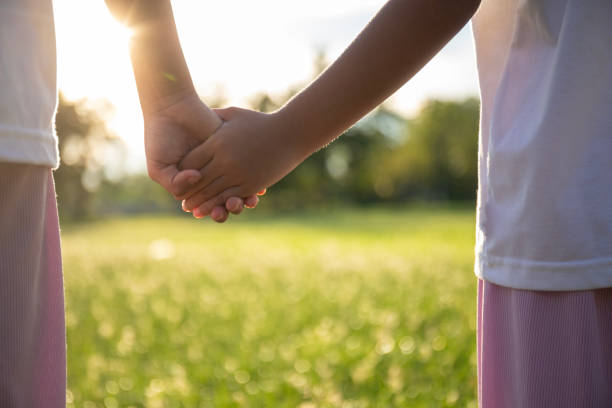 istock Two children holding hands in a grassy field. 2168930118