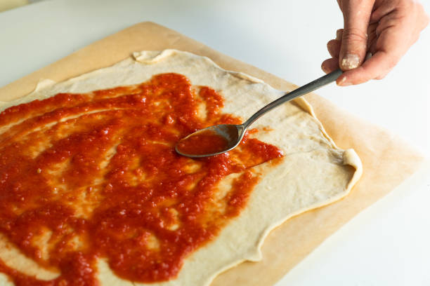 istock Spreading tomato sauce on pizza dough 2168941667