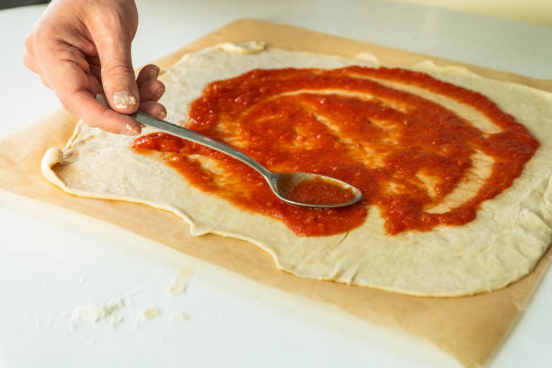 istock Spreading tomato sauce on pizza dough 2168941743