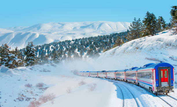 istock Red diesel train (East express) in motion at the snow covered railway platform - The train connecting Ankara to Kars - Passenger train going through tunnel 2168945311