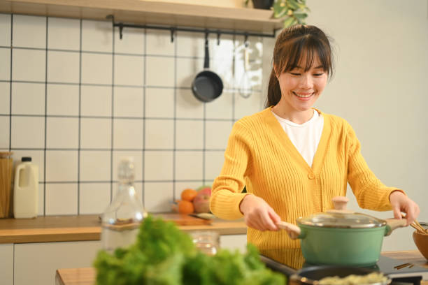 istock Smiling young woman enjoying her cooking process in minimal kitchen interior 2168951972