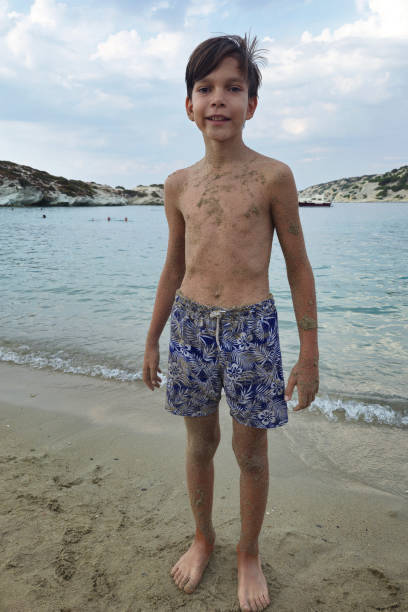 cute boy with sand on his body on the beach
