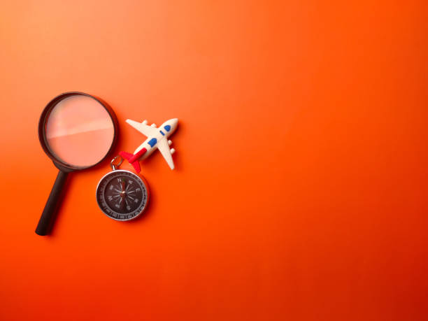 Top view compass, magnifying glass and toy air plane on a orange background