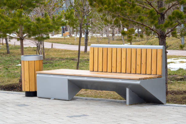istock Wooden bench with backrest and trash can on sidewalk in city 2168960791