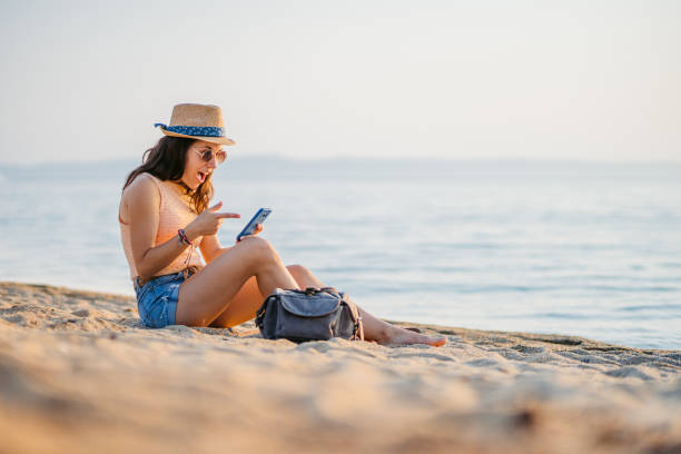 istock Young Woman Using Her Phone While Sitting On The Beach In Neos Marmaras In Greece 2168960977