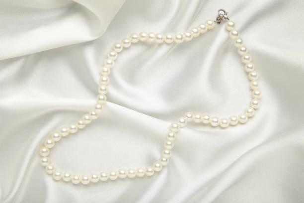 Pearl necklace on white silk background. Space for text
