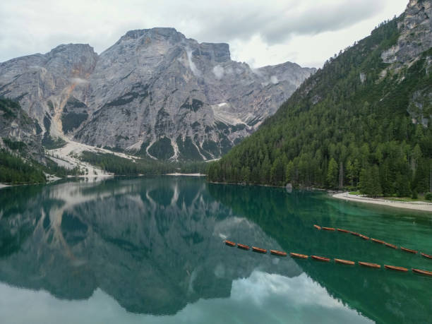 A stunning view of a pristine mountain lake reflecting majestic peaks and dense forests, with calm, crystal-clear water creating a peaceful and awe-inspiring natural landscape.