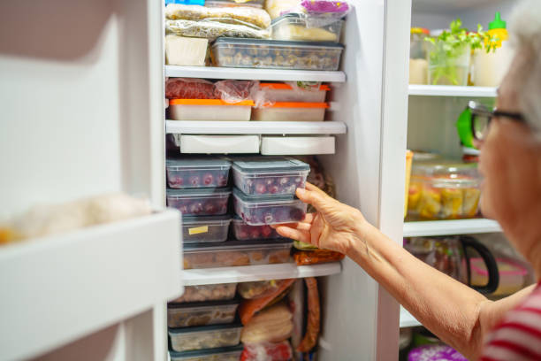 istock An elderly woman is arranging storage containers in her freezer. 2168969160