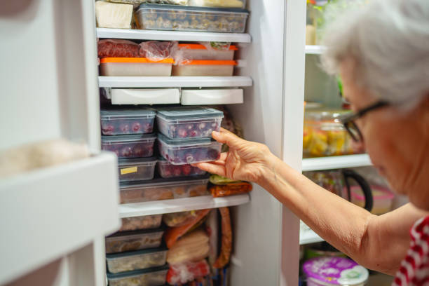 istock An elderly woman is arranging storage containers in her freezer. 2168969187