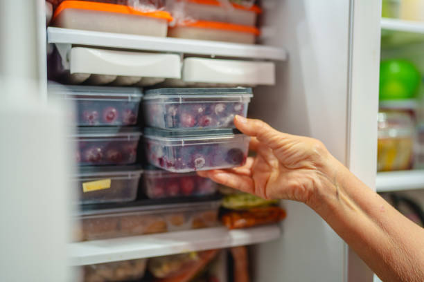 istock An elderly woman is arranging storage containers in her freezer. 2168969657