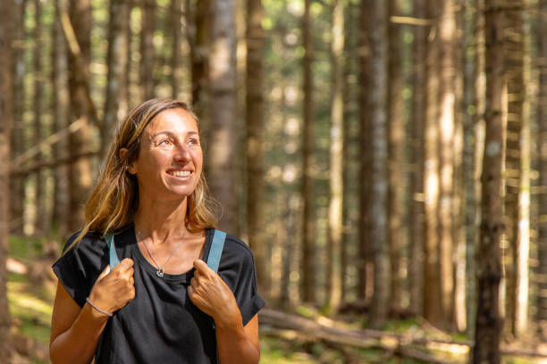 istock Woman Hiking Through Tall Trees in Sunlit Forest 2168975711