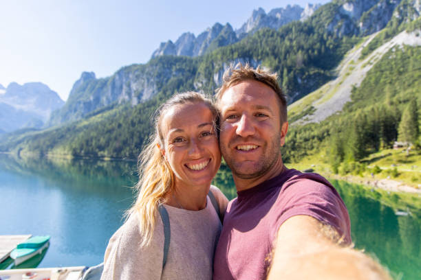 istock Smiling Couple Taking a Selfie by a Mountain Lake 2168976271