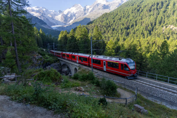 istock Red Train Crossing Bridge in Scenic Alpine Landscape 2168979951