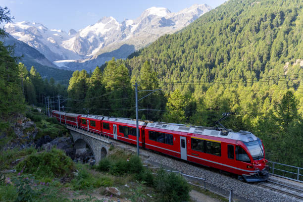 istock Red Train Crossing Bridge in Scenic Alpine Landscape 2168979952