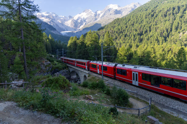 istock Red Train Crossing Bridge in Scenic Alpine Landscape 2168979992