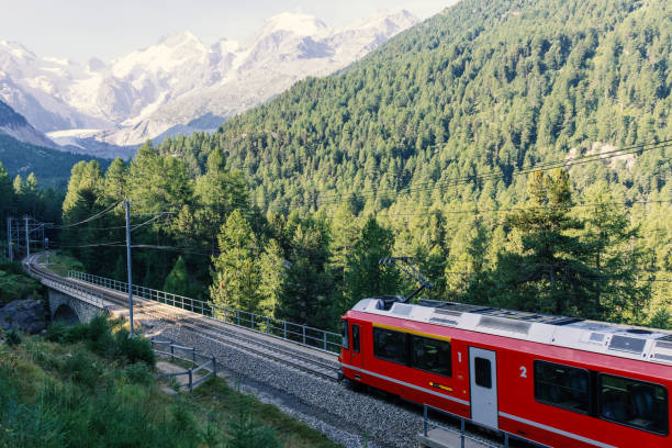 istock Red Train Passing Through Alpine Landscape with Snow-Capped Peaks 2168980054